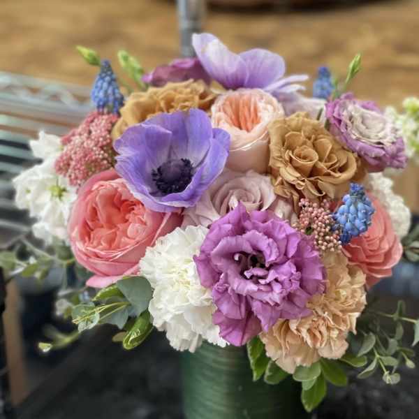Mixed bouquet of pastel flowers in a green vase