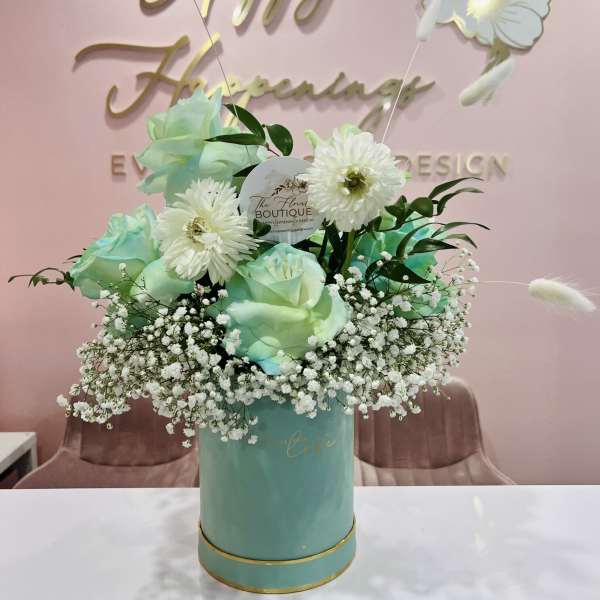 Mint roses and white daisies in a teal hatbox