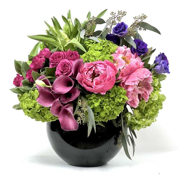 Pink and purple floral arrangement in a black vase