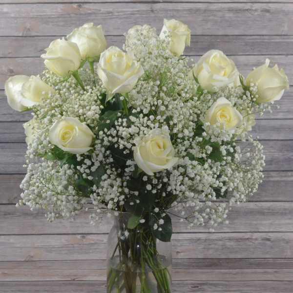 White roses and baby's breath in a clear glass vase