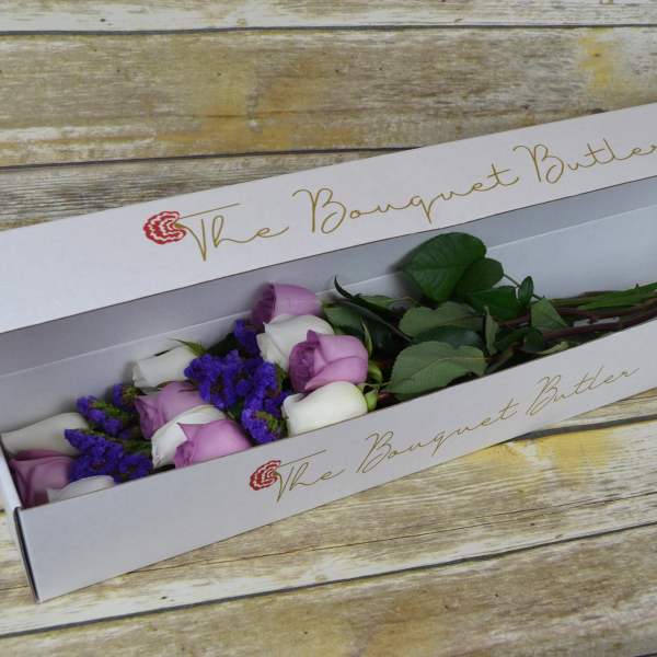 Boxed bouquet of lavender and white roses with purple filler