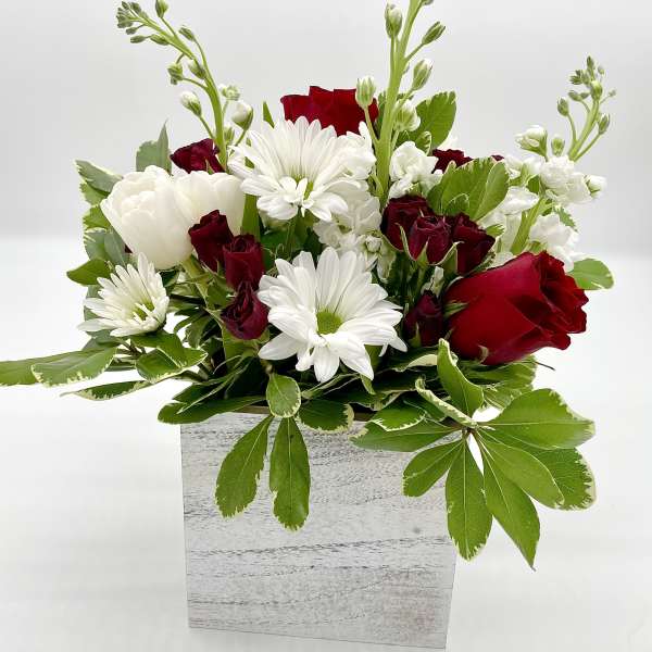 Red roses and white daisies arranged in a white wooden box