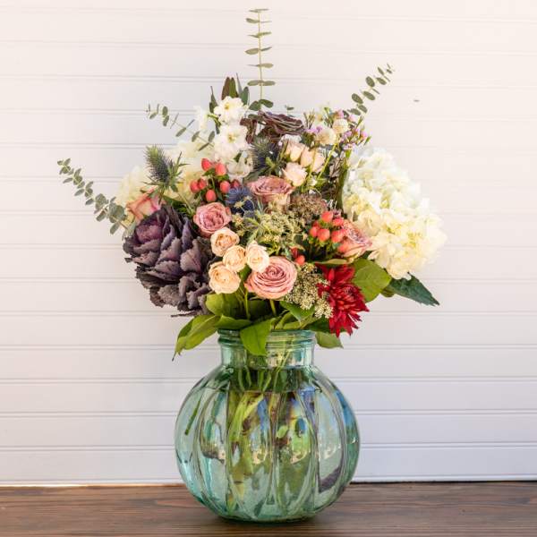 Mixed bouquet in a green glass vase with pink, white, and red blooms