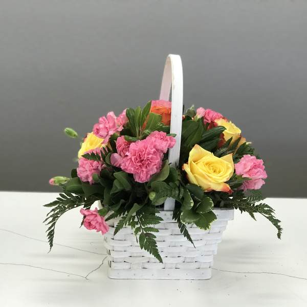Pink carnations and yellow roses in a white basket