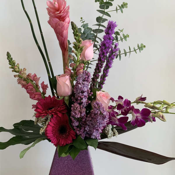 Tall mixed bouquet with pink and purple flowers in a purple vase