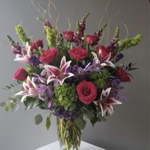 Bouquet of pink roses and purple lilies in a clear glass vase