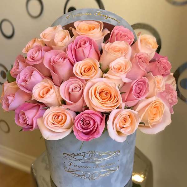 Round hat box of pink and peach roses arranged tightly together