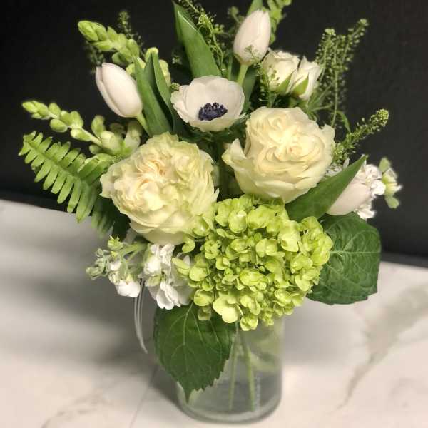 White and pale green floral arrangement in a glass vase