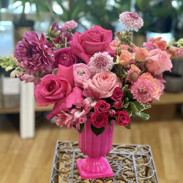 Pink and peach mixed flower arrangement in a bright pink vase