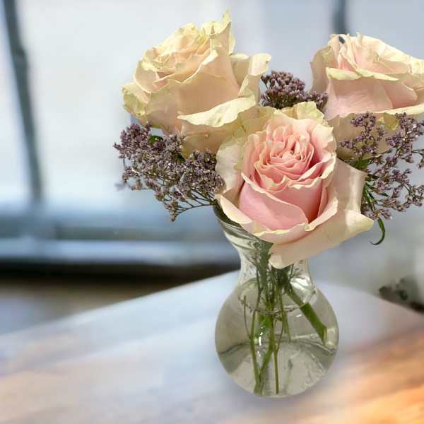 Pink roses and purple filler flowers in a clear glass vase