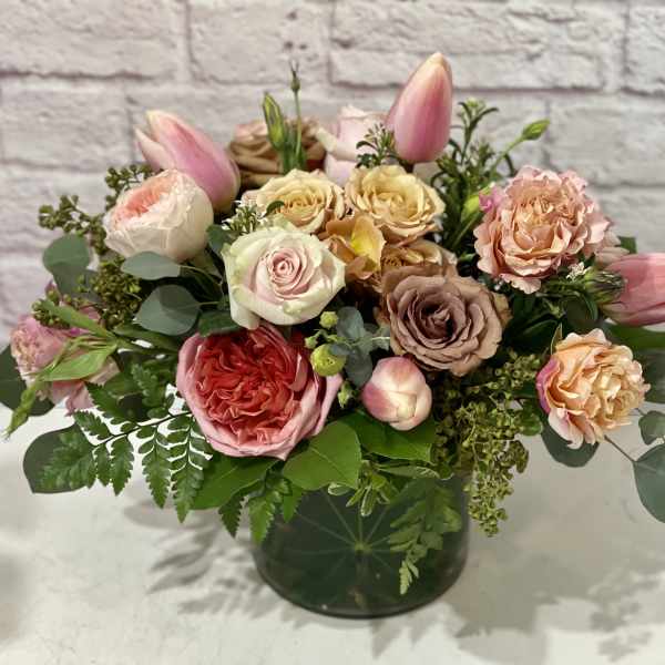 Pink and peach roses with tulips in a dark glass vase