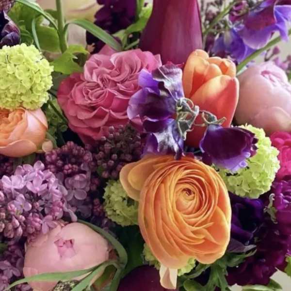 Vibrant mixed bouquet with pink roses, orange ranunculus, lilac, and purple blooms