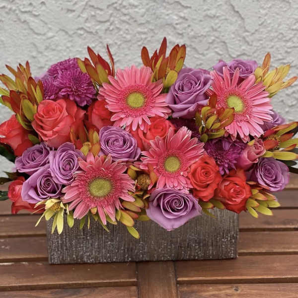 Pink and purple bouquet with roses and gerbera daisies in a rectangular box