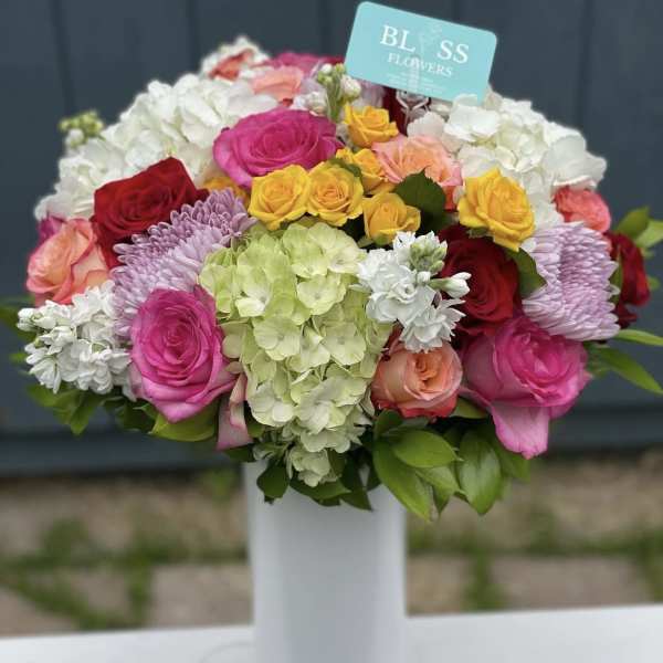 Mixed bouquet of roses, hydrangeas, and chrysanthemums in a white vase