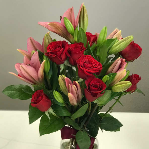 Bouquet of red roses and pink lilies in a glass vase