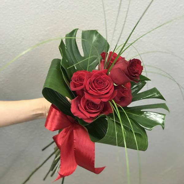 Red rose bouquet with tropical leaves and a red ribbon