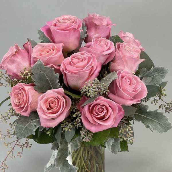 Pink rose bouquet in a clear glass vase with gray-green foliage