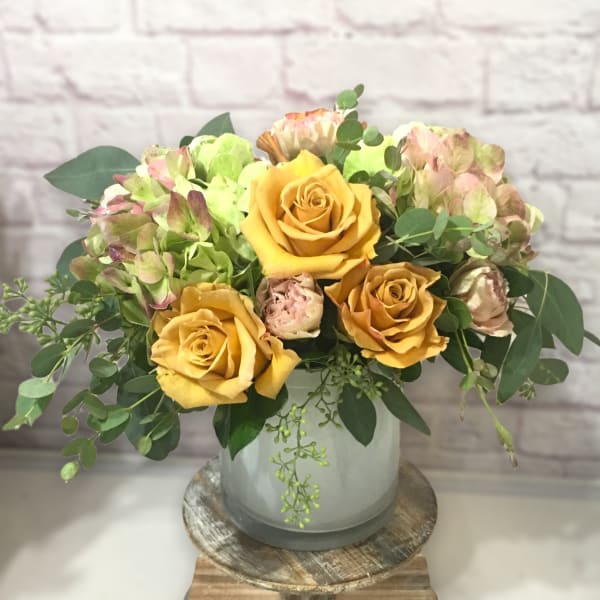 Yellow roses and pale hydrangeas in a glass vase