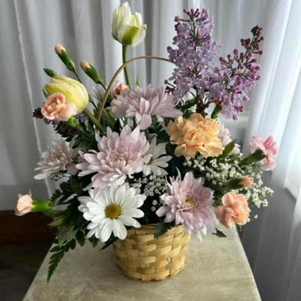 Basket arrangement of pastel flowers with daisies and lilac blooms