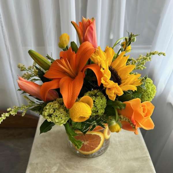 Orange and yellow floral arrangement in a clear glass vase