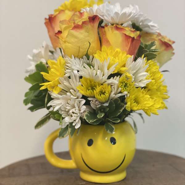 Yellow and white flower bouquet in a yellow smiley-face mug