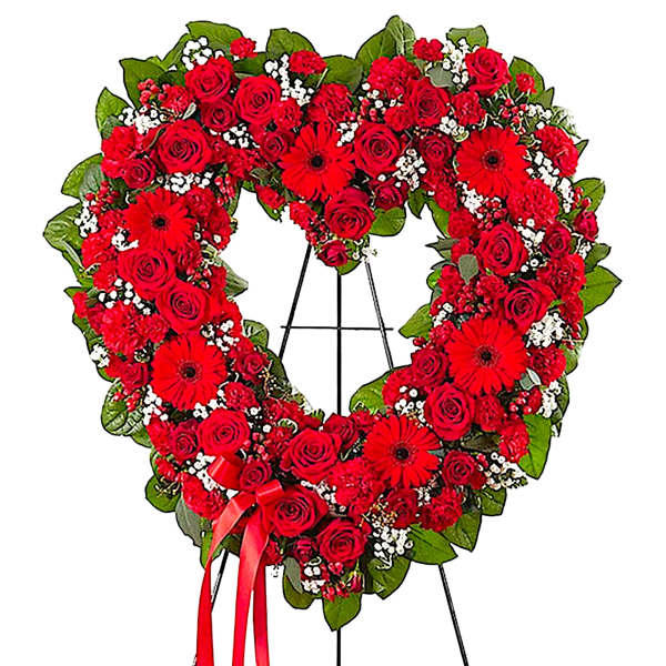 Heart-shaped red rose wreath on a black easel with a red ribbon