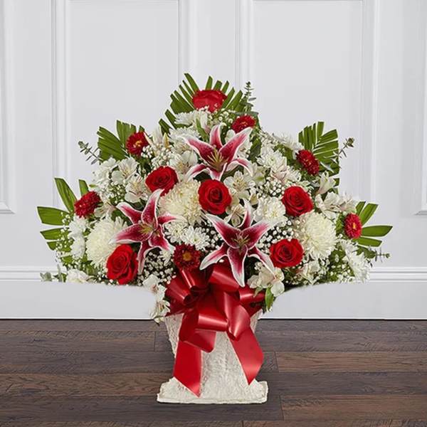 Red roses and white lilies in a white basket with a red ribbon
