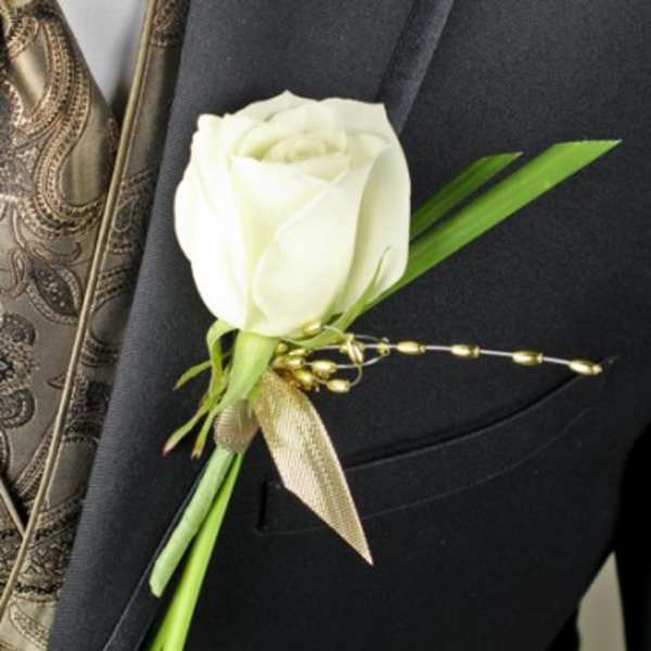 White rose boutonniere with green accents on a dark suit lapel