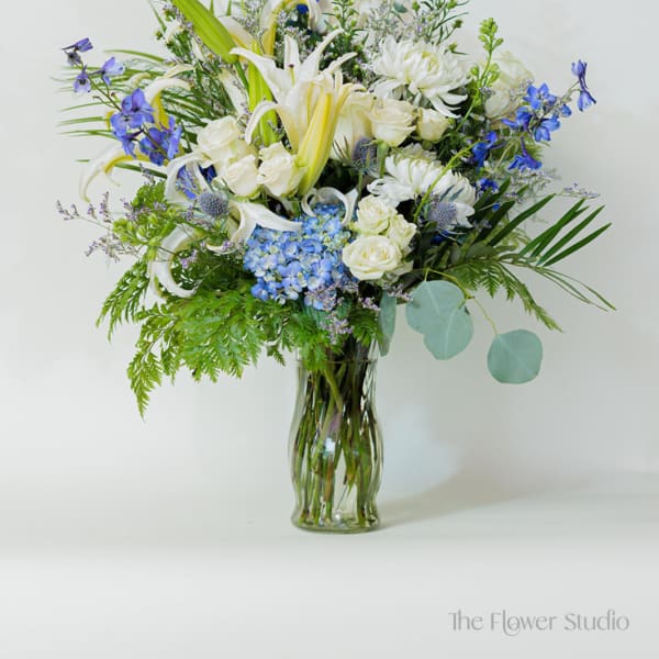 Blue and white mixed flower arrangement in a glass vase