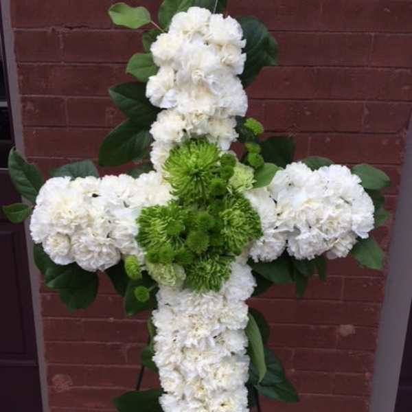 White and green floral cross arrangement on a stand