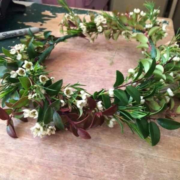 Floral crown with small white blossoms and mixed greenery on a table