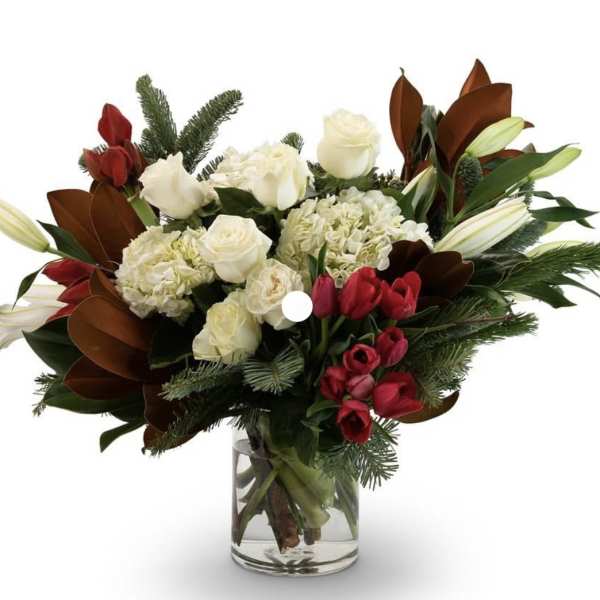 Bouquet of white roses, hydrangeas, and red tulips in a glass vase