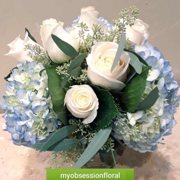 Bouquet of white roses and blue hydrangeas with greenery