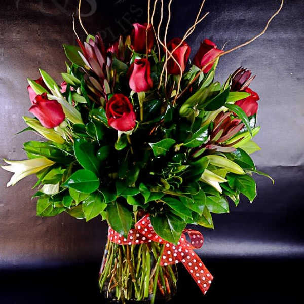 Red roses arranged in a clear glass vase with a polka-dot ribbon