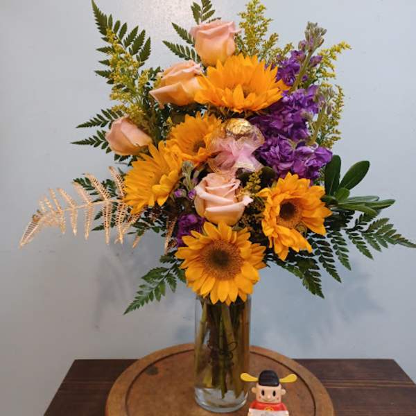 Sunflower and peach rose arrangement in a glass vase