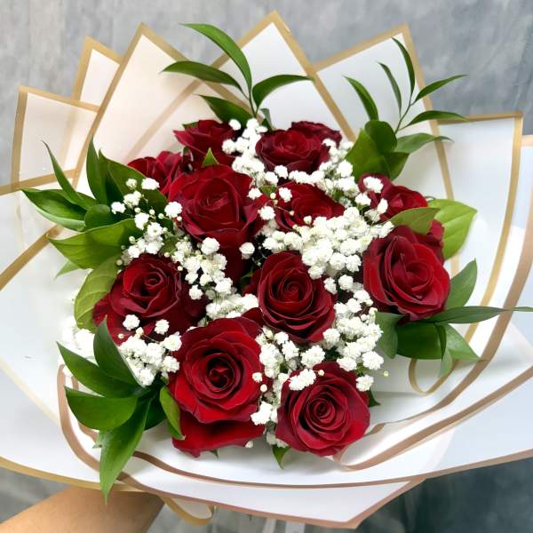Bouquet of red roses with white baby's breath in white and gold wrap