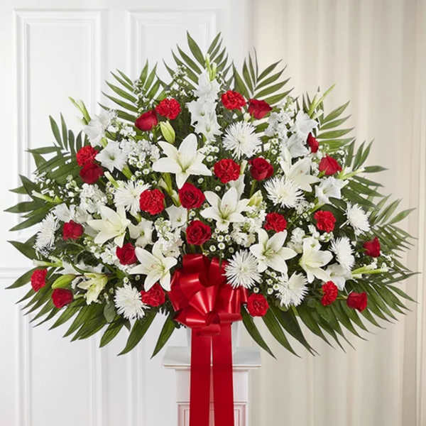 Large standing spray of red and white flowers with a red ribbon