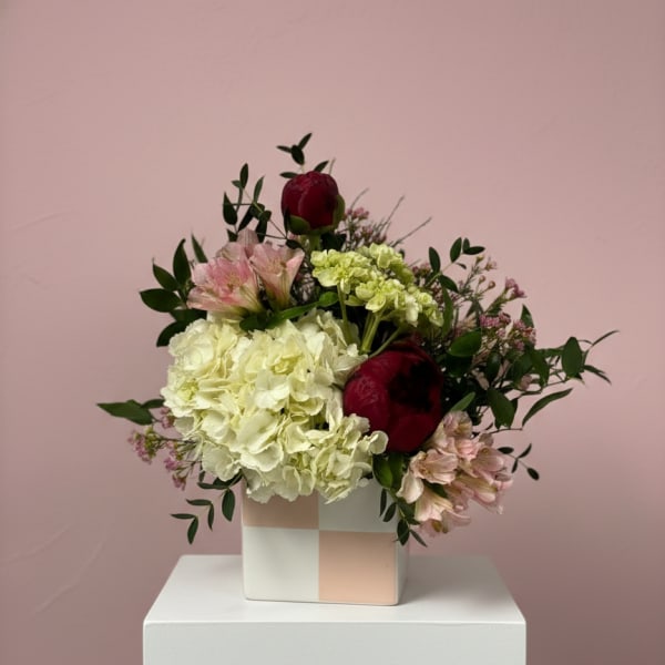 Bouquet of hydrangeas and red roses in a square vase