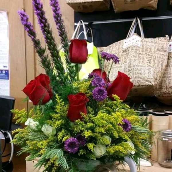 Bouquet of red roses and purple flowers in a white flower pot