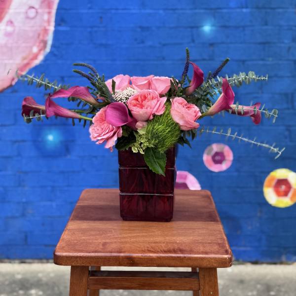 Pink roses and calla lilies in a dark glass vase