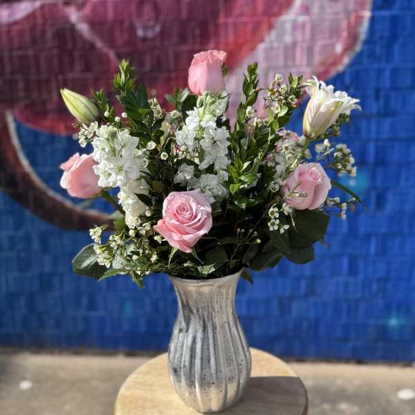 Pink roses and white flowers arranged in a silver vase