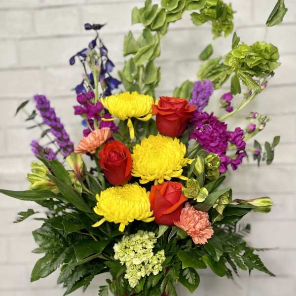 Colorful mixed flower arrangement in a tall burgundy vase