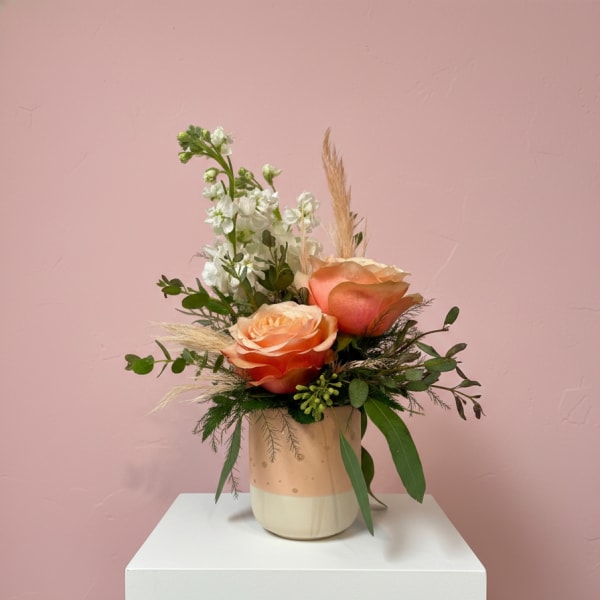 Peach roses in a ceramic vase with white filler flowers