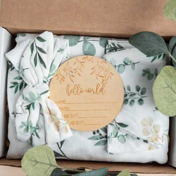 Folded baby blanket set with a wooden hello world milestone disc