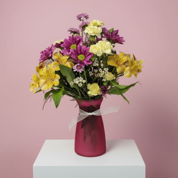 Mixed bouquet in a magenta vase with yellow and purple flowers