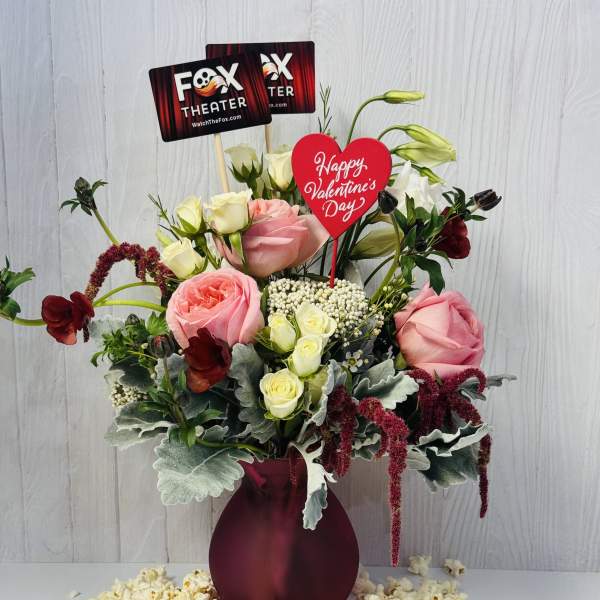Pink and white rose arrangement in a burgundy vase with Valentine signs