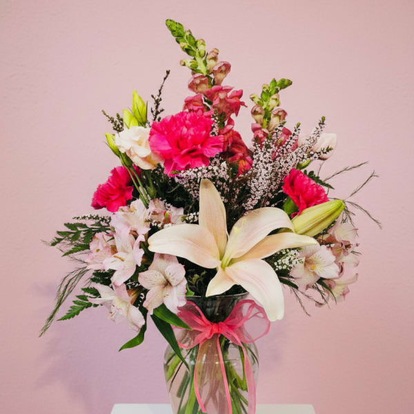 Bouquet of lilies, pink carnations, and snapdragons in a glass vase