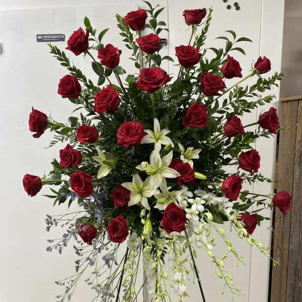 Tall standing spray of red roses and white lilies on a metal easel