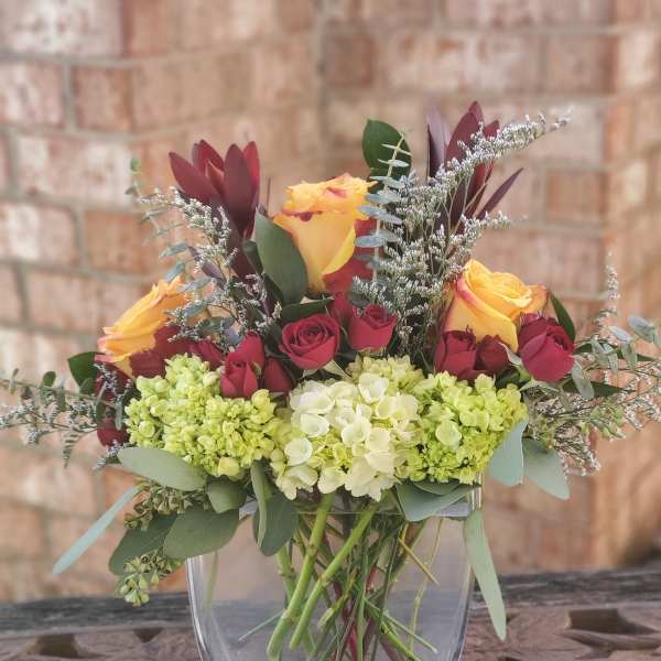 Bouquet of yellow and red roses in a clear glass vase