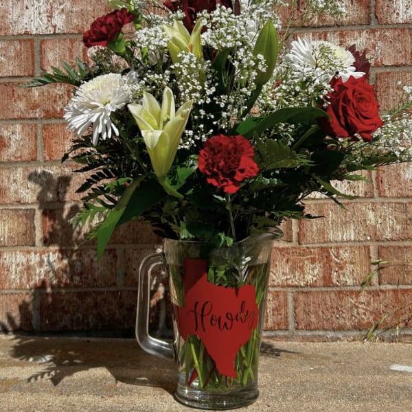 Red and white mixed flower arrangement in a glass pitcher